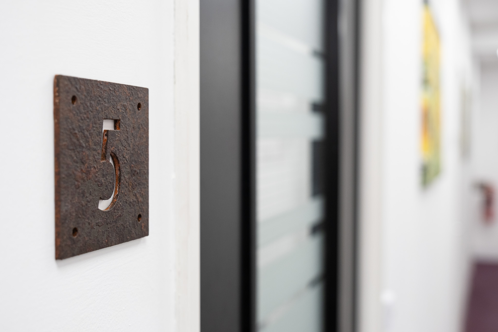 Close up on door sign number 5 with corridor in background