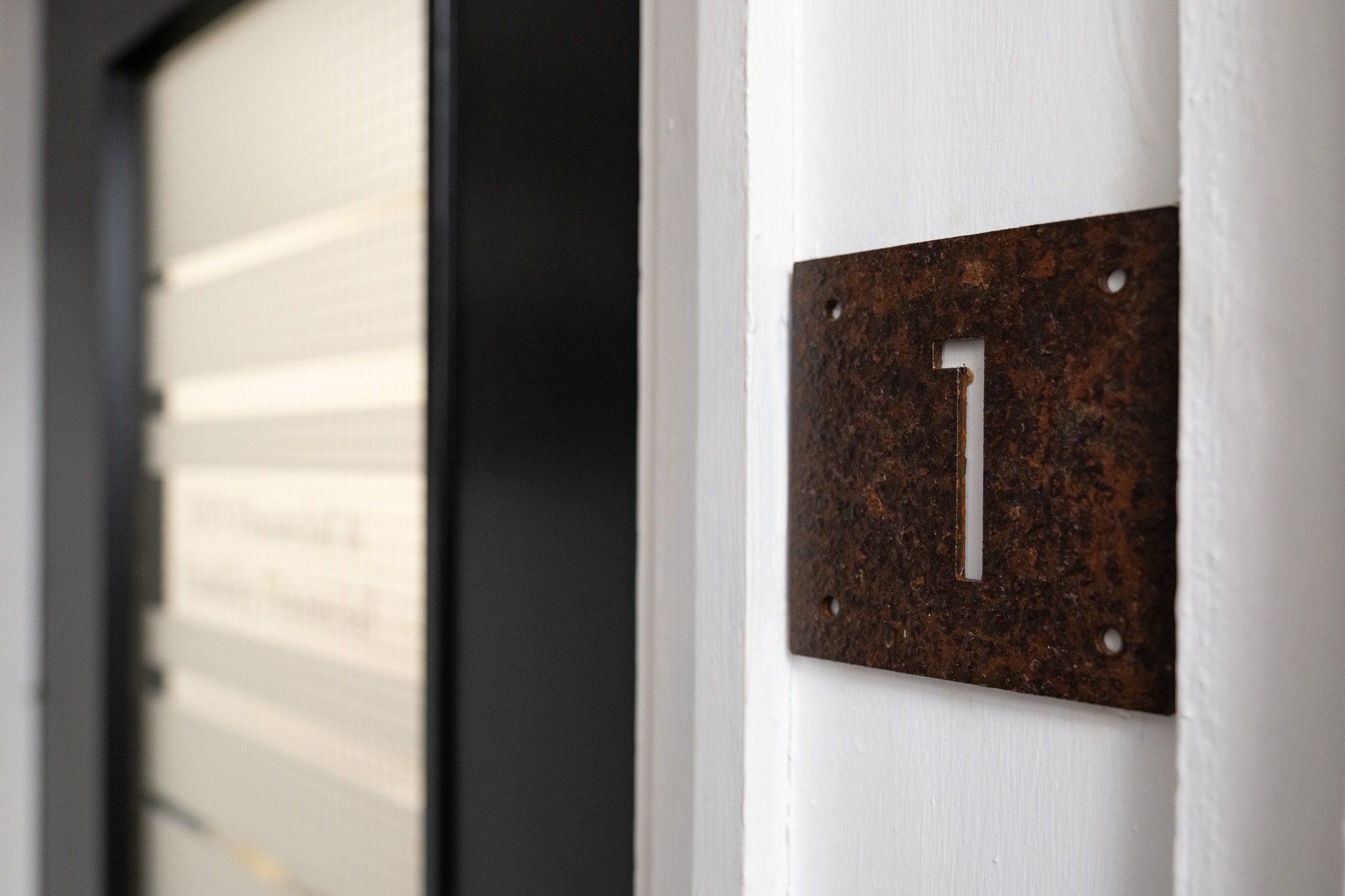Close up on door sign number for office 1, 3 Tannery House with corridor in background