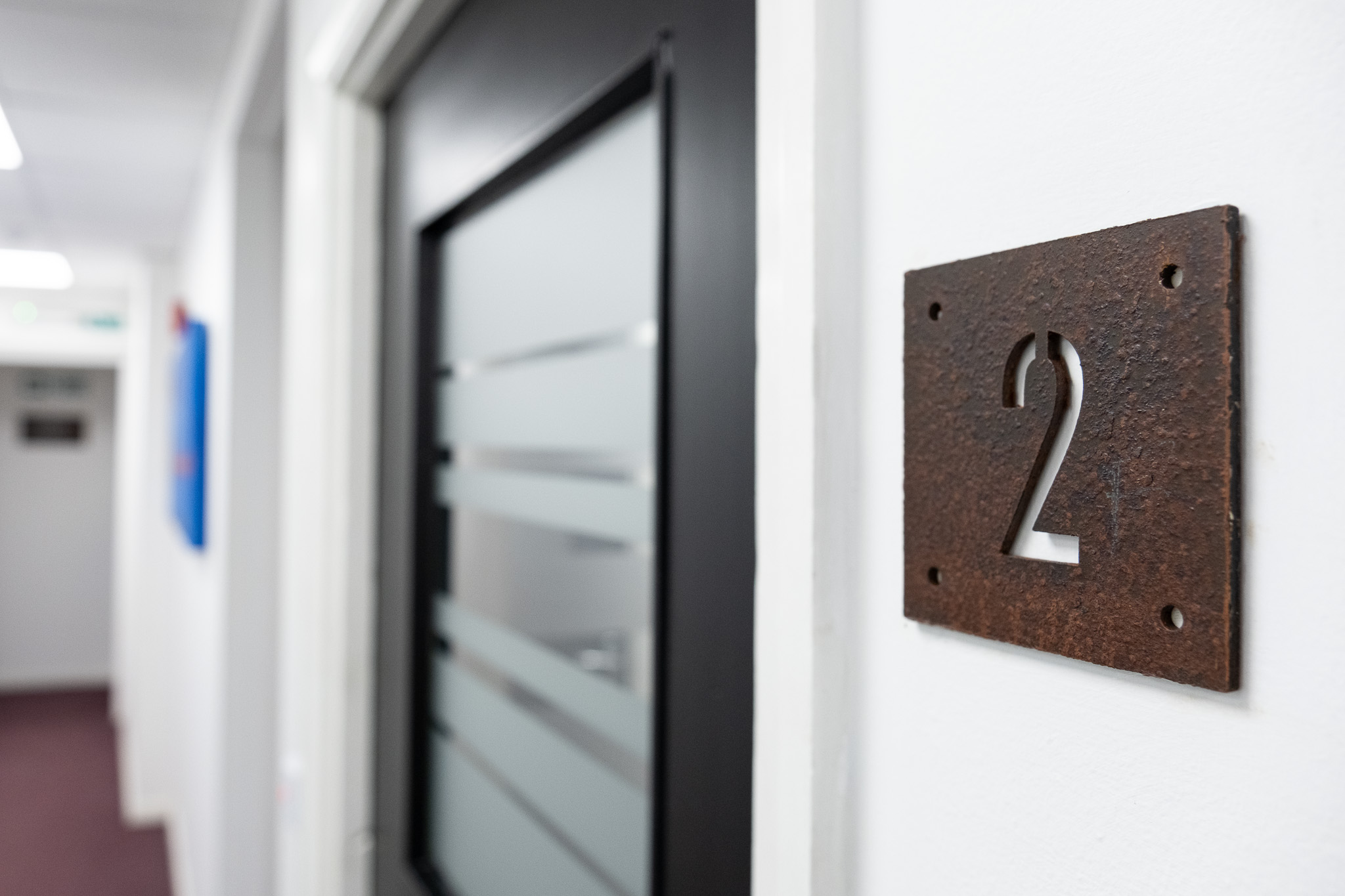 Close up on door sign number for office 2, 3 Tannery House with corridor in background
