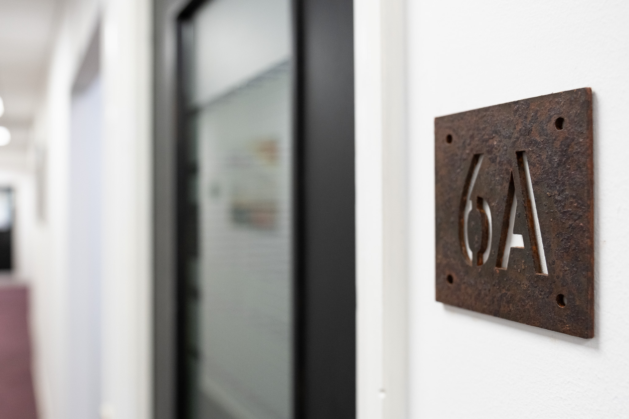 Close up on door sign number for office 6A, 4 Tannery House with corridor in background